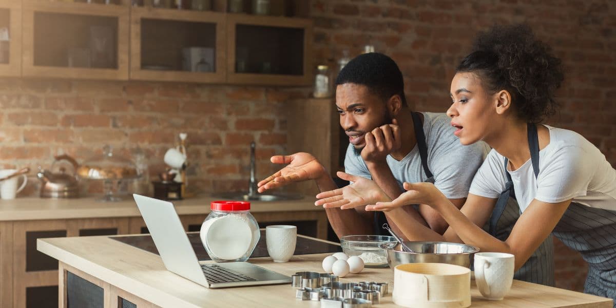 Confused couple looking at screen trying to cook